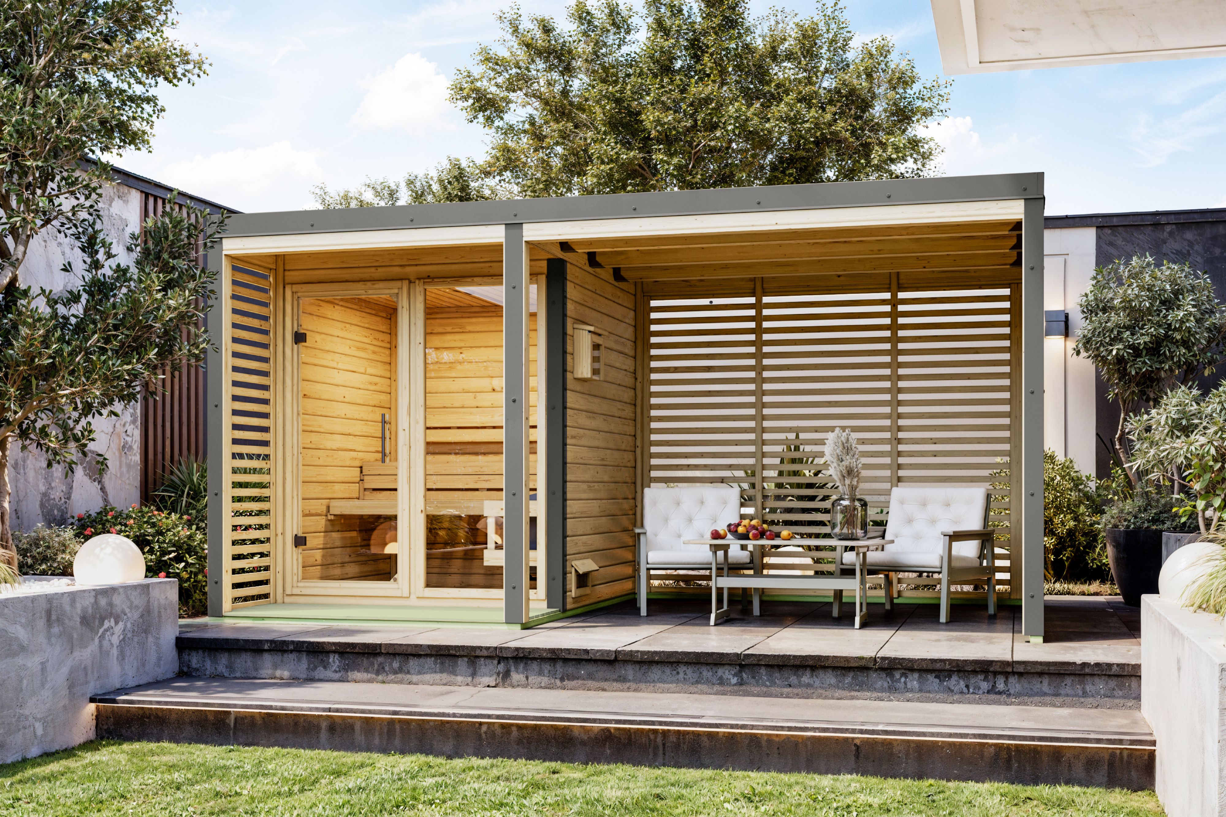 Karibu Saunahaus Ares 1 mit 2,70 m Anbaudach als Gartensauna aus Massivholz im Garten mit Glasfront